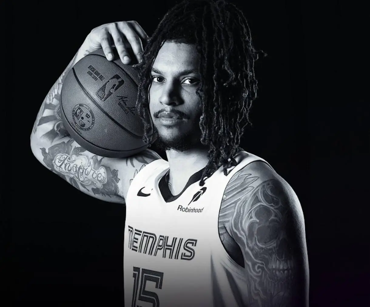 Portrait of a tattooed basketball player with dreadlocks, holding a ball on his shoulder in a Memphis Grizzlies jersey.