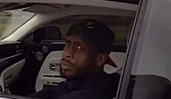 Man in a dark cap sits in the driver's seat, glancing toward the camera.