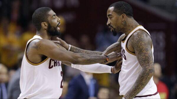 Two Cavaliers players in white jerseys touch chests in a game moment on the court, facing each other.