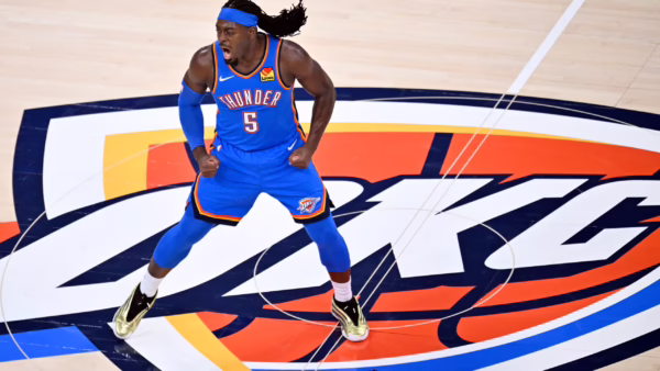 Basketball player in a blue Thunder jersey, fists clenched, mid-jump on a colorful court logo background