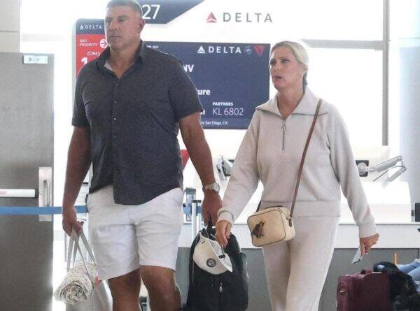 Two travelers walking through an airport check-in area, pulling rolling bags with Delta signage in the background.