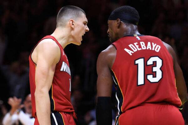 Two basketball players in red jerseys argue on the court during a game, with the number 13 visible on the back of one player's jersey.