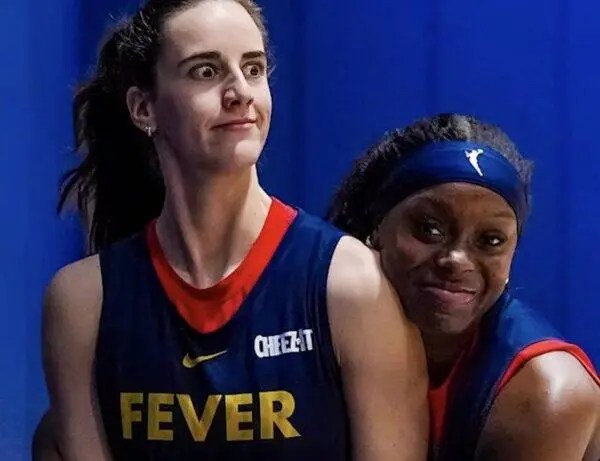 Two female basketball players in navy Fever uniforms pose against a blue background; the left player looks upward with wide eyes.