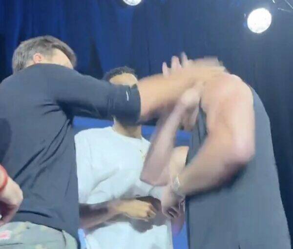Group of men on a stage celebrating, reaching hands together in a high-five/motion shot.