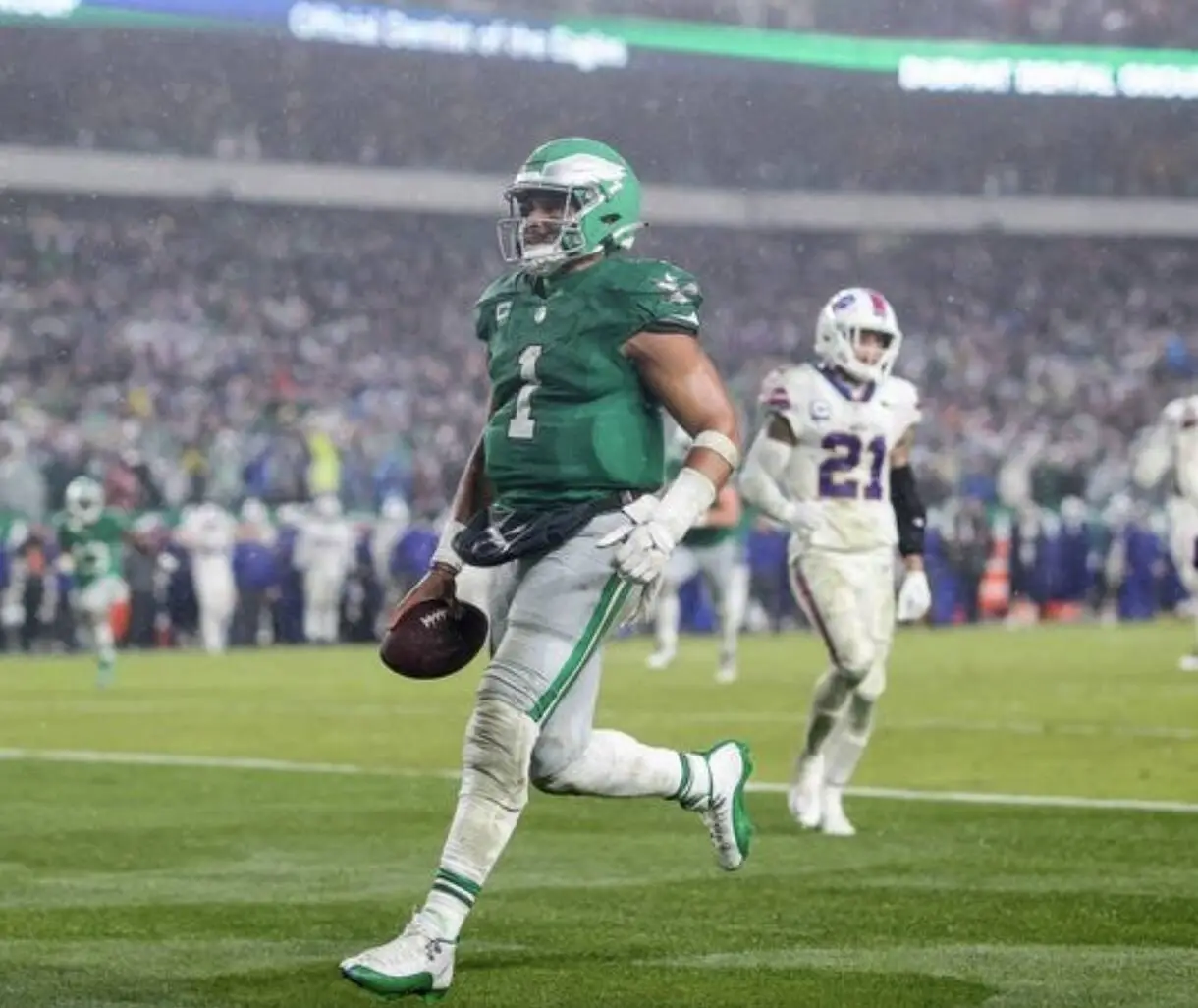 Philadelphia Eagles player in green #1 running with the ball downfield as a defender pursues nearby.