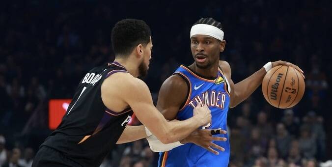 Two basketball players collide for the ball during a game: one in a blue Thunder jersey with a headband holds the ball while a defender in a dark jersey guards him.