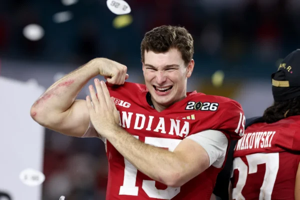 Indiana football player celebrating a win, flexing arm with a big grin on his face amid confetti.