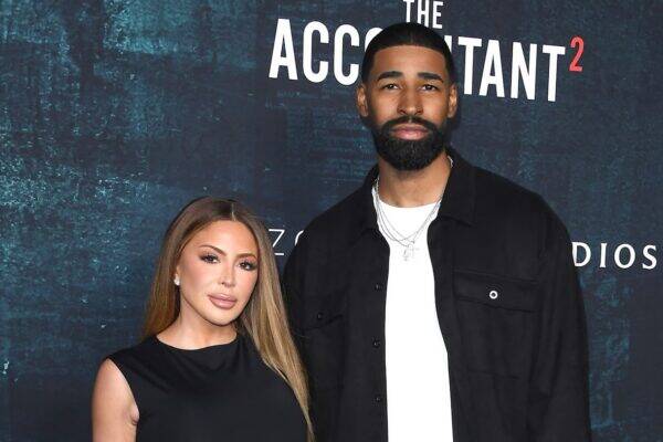 Kim Kardashian (left) and a tall bearded man pose on the red carpet in front of a dark blue backdrop with The Accountant 2 text.