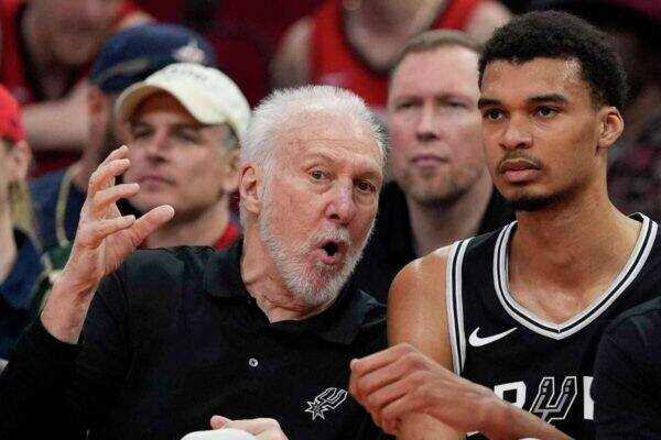 San Antonio Spurs coach Gregg Popovich speaks animatedly to a player during a game on the sideline.