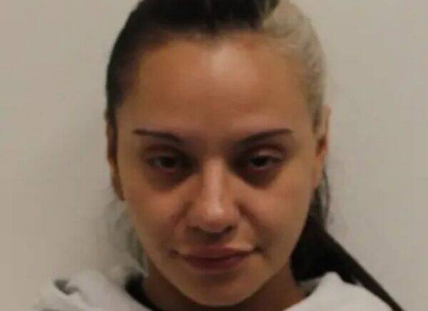Close-up photo of a young woman with dark hair tied back, wearing a white hoodie, facing the camera with a neutral expression against a plain background.