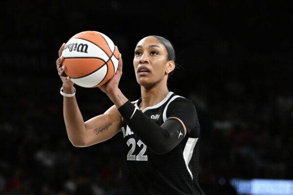 Female basketball player in a black jersey with number 22 holds an orange-and-white basketball, preparing to pass or shoot.