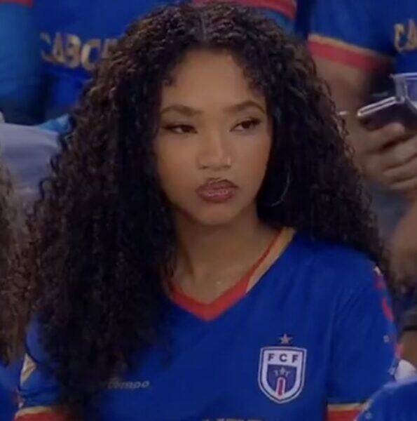 Young woman with long curly hair in a blue jersey with an FCF crest, looking to the side.