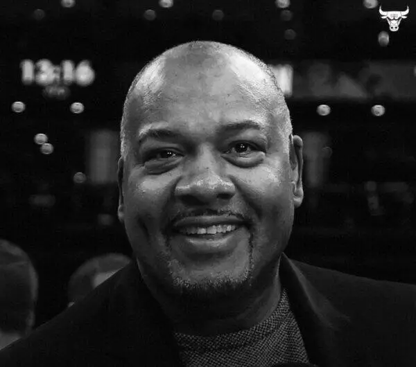 Staff headshot: smiling Black man in a dark blazer, black-and-white portrait.