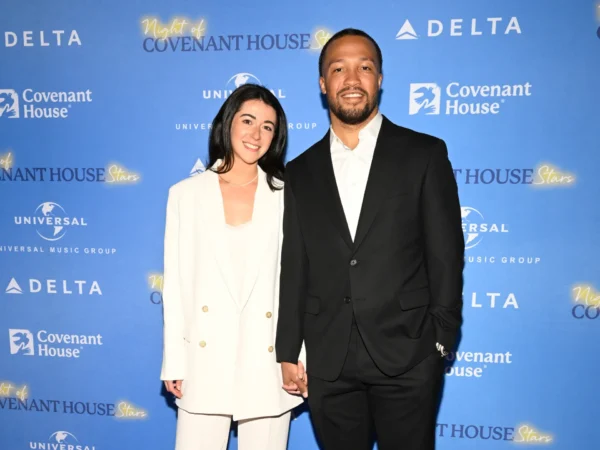 Couple posing on a blue Covenant House Stars backdrop, holding hands and smiling at the camera.
