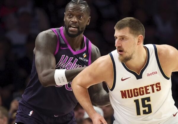 Basketball players in action: Nuggets center wearing white jersey #15 defended by an opponent in a purple uniform during a fast move on the court.