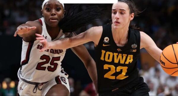 Two female college basketball players sprint toward the ball; Iowa player #22 in black drives while South Carolina player #25 in white defends.