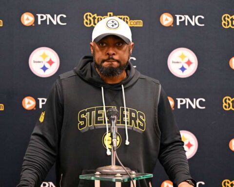 Man in a Steelers hoodie at a press conference podium, microphone in front, backdrop with Steelers and PNC logos behind him.