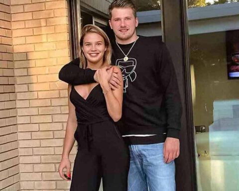 Couple posing together outside a brick storefront, the man's arm around the woman's shoulders as they smile at the camera.