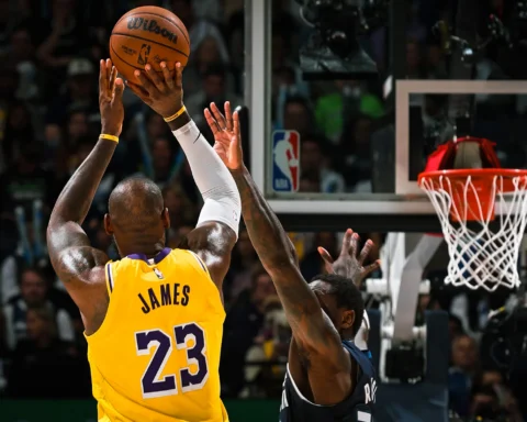 LeBron James (#23) in a Lakers jersey goes up for a shot near the basket as defenders contest the play.