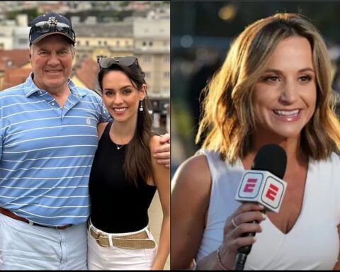 Smiling older man in a blue striped polo and cap posing with a younger woman in a black top outdoors near a cityscape.