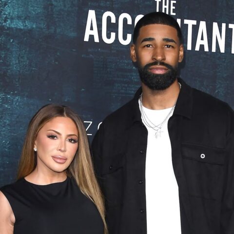 Kim Kardashian (left) and a tall bearded man pose on the red carpet in front of a dark blue backdrop with The Accountant 2 text.