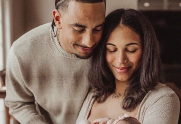 New parents cradle their newborn, sharing a tender moment indoors.