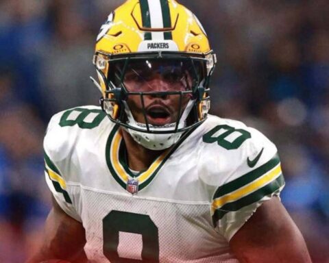 Green Bay Packers football player in a white jersey (number 8) and yellow helmet, running on the field during a game.