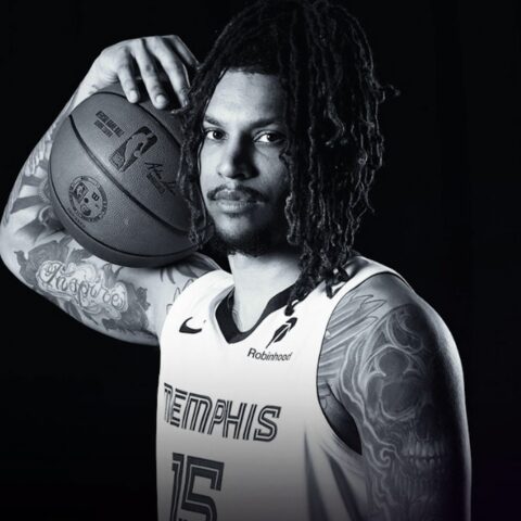 Portrait of a tattooed basketball player with dreadlocks, holding a ball on his shoulder in a Memphis Grizzlies jersey.