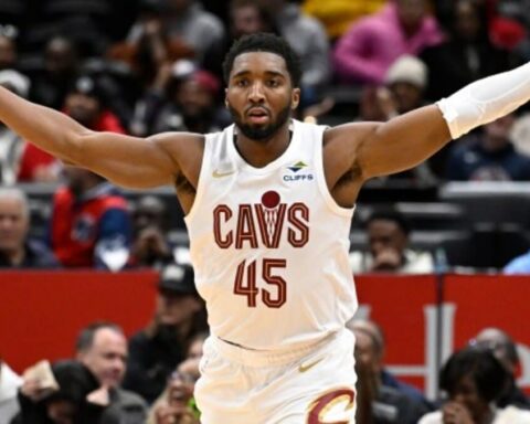 Basketball player in a white Cavs jersey number 45 with arms outstretched during a game on a crowded court.