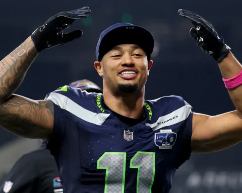 Seattle Seahawks football player wearing number 11 jersey, arms raised in celebration on the field.