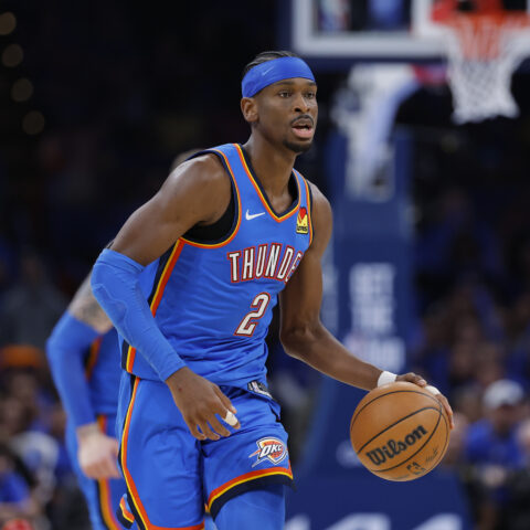 OKC Thunder guard in blue uniform dribbling a basketball during a game on the court with a crowd in the background