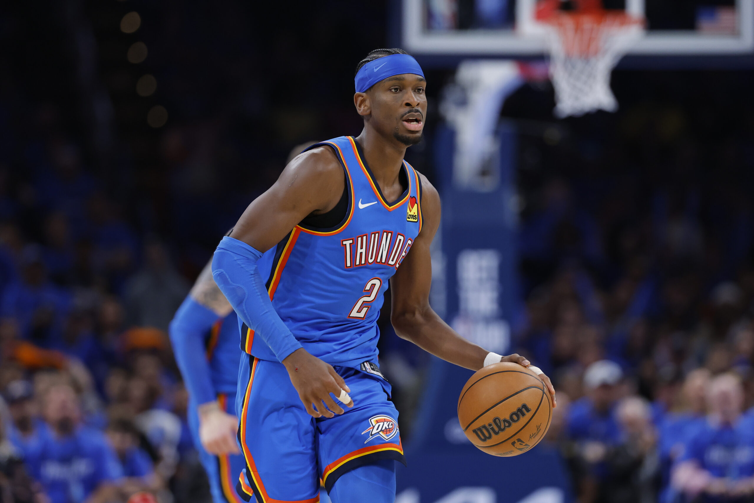 OKC Thunder guard in blue uniform dribbling a basketball during a game on the court with a crowd in the background