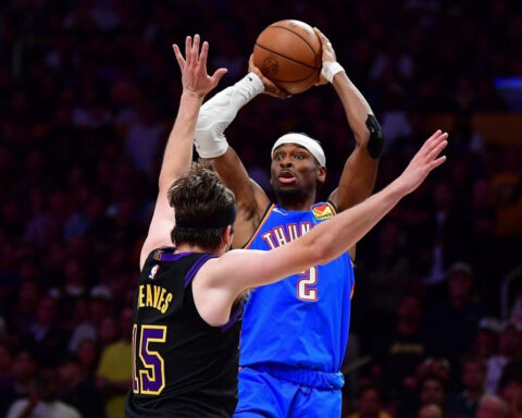 Basketball players leap for a shot: one in a blue Thunder jersey with number 2, the other in a dark jersey with number 15 trying to block.