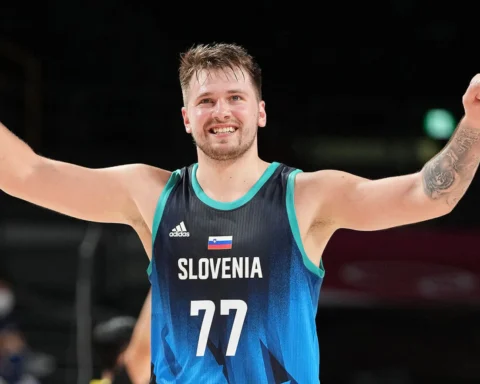 Slovenia basketball player with arms raised in celebration, wearing blue jersey and number 77 on the court.