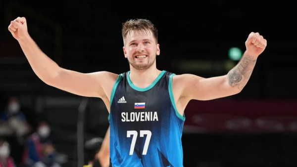 Slovenia basketball player with arms raised in celebration, wearing blue jersey and number 77 on the court.
