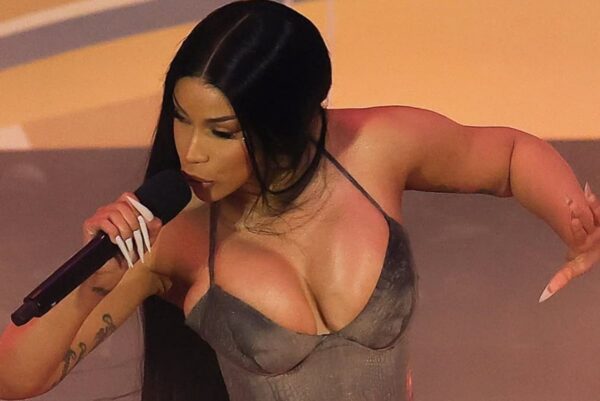 Female singer with long dark hair performing onstage, holding a microphone close to her mouth.