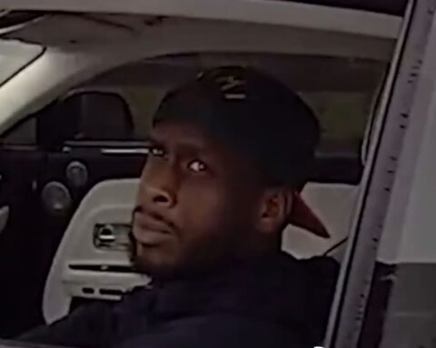Man in a dark cap sits in the driver's seat, glancing toward the camera.
