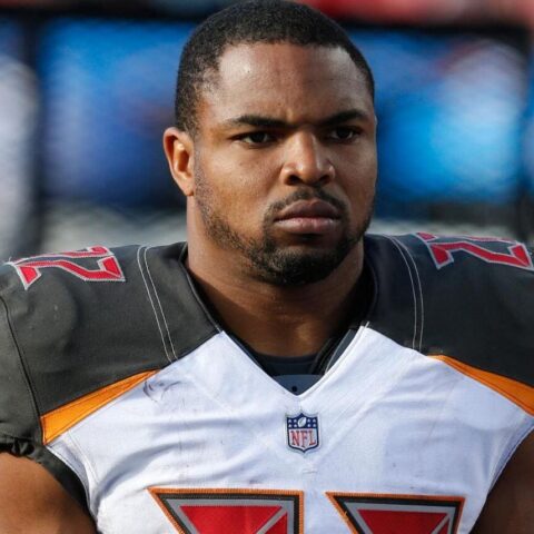 Close-up of a Black NFL player in a football uniform with orange accents, looking focused on the field.