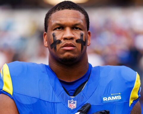 Close-up of a Rams football player wearing blue and yellow jersey with eye black, standing on the field.