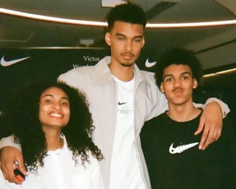 Three young friends posing together with their arms around each other, smiling at the camera, indoors at a Nike event.
