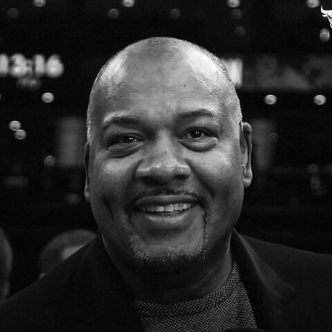Staff headshot: smiling Black man in a dark blazer, black-and-white portrait.