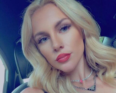 Close-up portrait of a young woman with blonde hair and pink lipstick inside a car