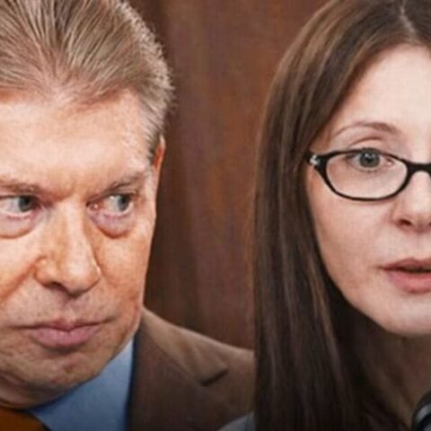 Man and woman in a press conference; the man looks sideways with a tense expression, the woman speaks into a microphone.