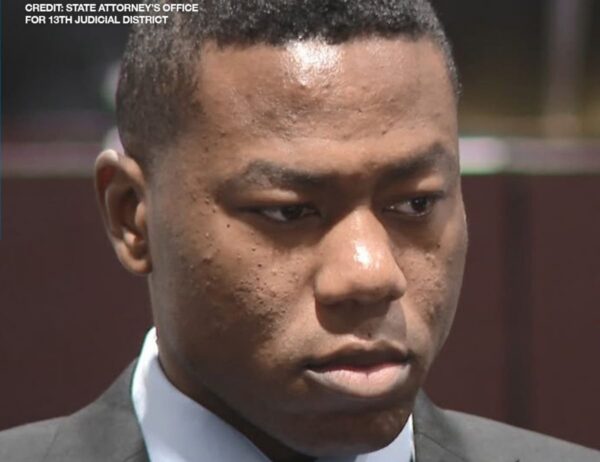 Close-up of a young man in a suit looking downward outdoors, with a State Attorney's Office credit in the top-left.