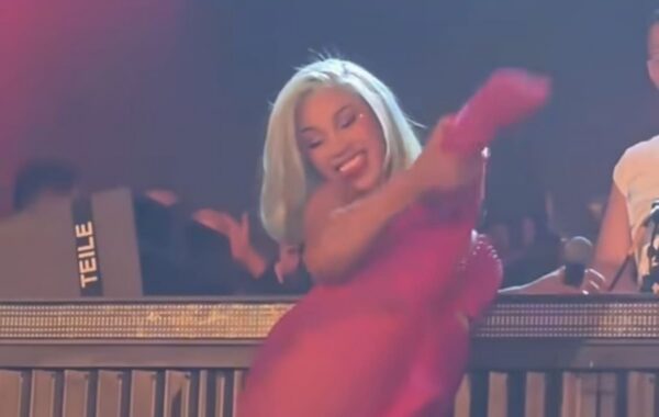 Performer in a bright pink dress dancing on stage, smiling at the crowd.