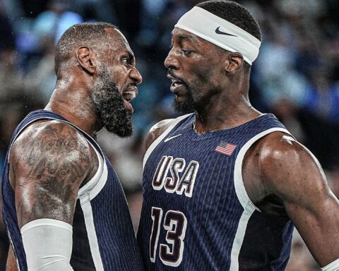 Two USA basketball players glare at each other on the court during a heated moment while wearing navy jerseys with white trim.