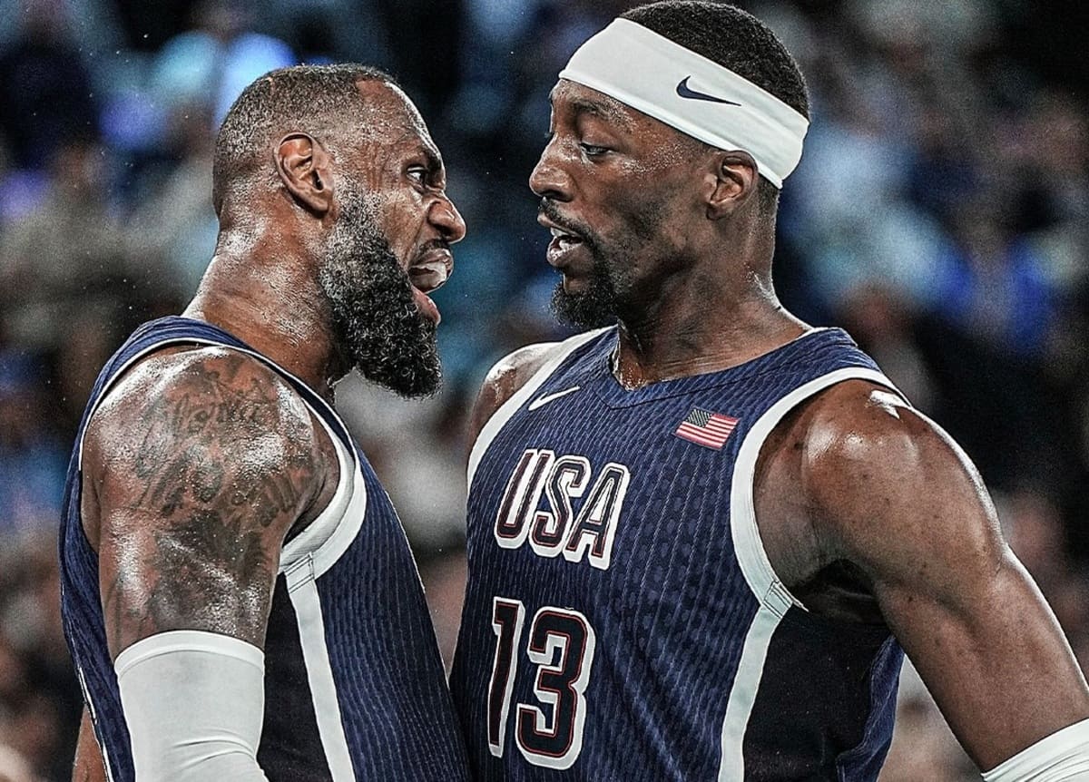 Two USA basketball players glare at each other on the court during a heated moment while wearing navy jerseys with white trim.