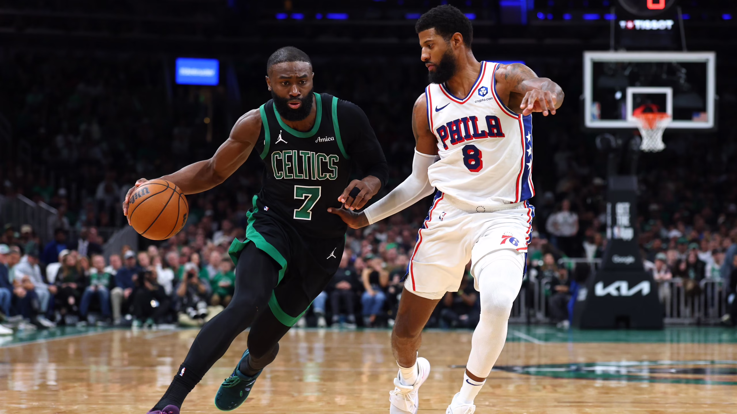 Two NBA players in a heated moment on the court, Celtics in green and 76ers in white chasing the ball amid a crowded arena.