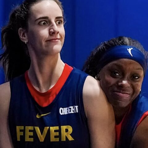 Two female basketball players in navy Fever uniforms pose against a blue background; the left player looks upward with wide eyes.