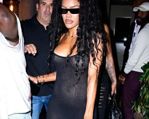 Woman with long curly hair in a tight black dress and sunglasses amid a crowded nightlife scene, carrying a small bag.